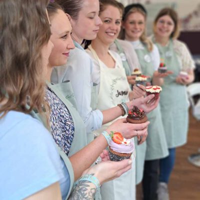 6 junge Frauen zeigen ihren kleinen Kuchen nach dem gemeinsamen Backen