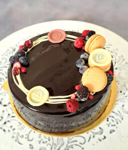 runde Schokoladentorte in braun , verziert mit 3 hellbraunen Macarons, 2 weißen Schokoladenherzen , Früchtedekoration aus Heidelbeeren, Brombeeren
